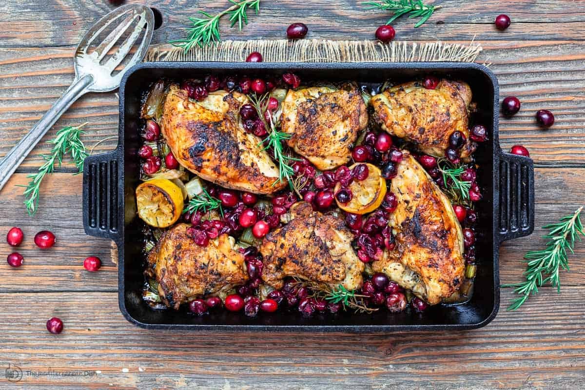 Finished baked cranberry chicken in pan, serving spatula to the side